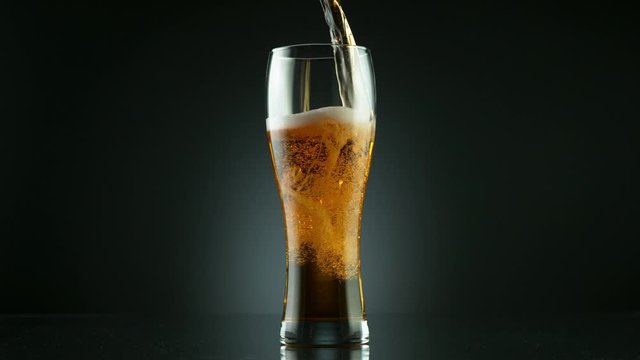 Super slow motion of pouring beer drink into glass, placed on black background. Filmed on high speed cinema camera, 1000 fps.