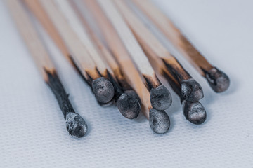 some burned matches lie side by side on a white base