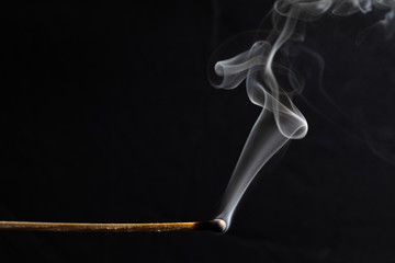 burned match still smoking against a black background