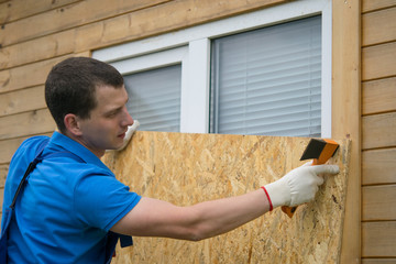 worker, boarded up the window of the house with a protective shield made of wood, from thieves,...