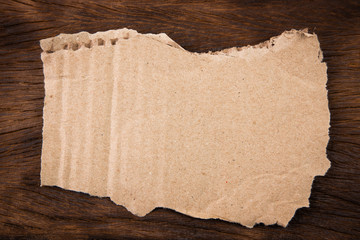Brown corrugated texture paper torn background with wood backdrop. rip of cardboard sheet used as a...