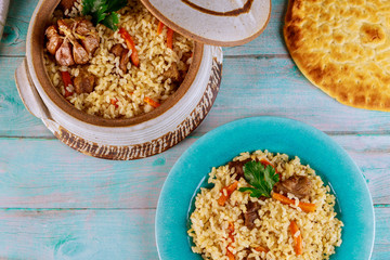 Uzbek pilaf with rice, meat, carrot and garlic in clay pot.