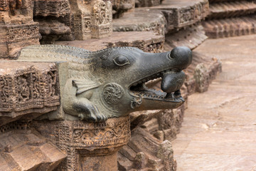 A water outlet in the shape of a crocodile, holding a fish in its mouth
