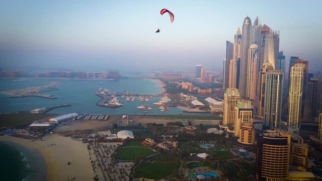 Powered paragliding paramotoring ppg flight with parachute on spectacular aerial Dubai beach modern building cityscape
