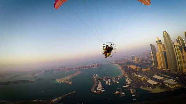 Paramotoring powered paragliding ppg flight high in beautiful evening sunset sky on calm blue Dubai beach ocean seascape