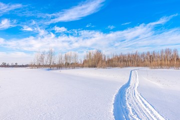 Snowmobile road on a snowy field. Winter landscape on a bright sunny day