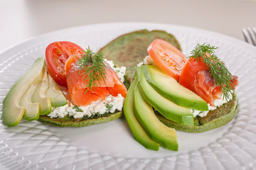 Close-up Pancakes with spinach, curd cheese, avocado and smoked salmon. Tasty and healthy breakfast