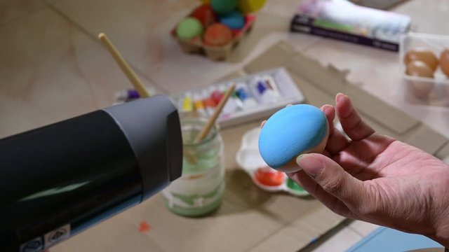people using dryer blowing easter egg handicraft to dry color