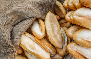 Loaves of a freshly baked baguette for sale, covered with sackcloth. Close-up view from the top. 