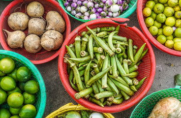 Typical Asian street market for fruits and vegetables. Close up and top view of vegetables for sale in round plastic containers.  