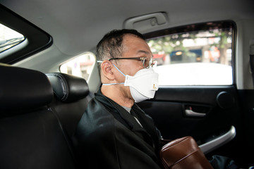 Man wearing spectacles and N95 mask for protect PM 2.5 dust and serious of the air pollution while sitting and waiting for the bus at the bus stop with crutches or support stick in Bangkok Thailand.