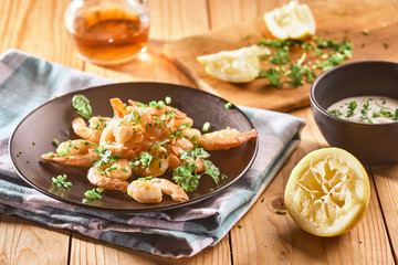 shrimp in a black plate with lemon and green onions