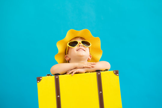 Portrait of happy child with yellow suitcase. Summer vacation concept