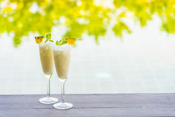 Ice cocktails glass on wooden floor around outdoor swimming pool
