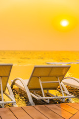Empty chair around outdoor swimming pool in hotel resort at sunset or sunrise time