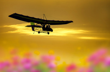 A microlight aircraft with two passengers with the sun and cloud, Ultralight trike