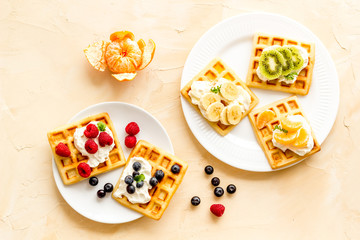Fototapeta na wymiar Belgian waffles with creamy cheese and berries on beige background top-down
