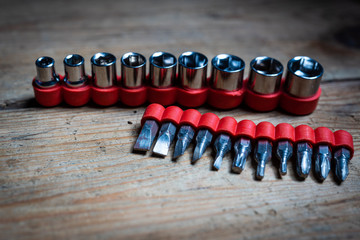 Inserts of a socket spanner with a red cap lying on a wooden surface