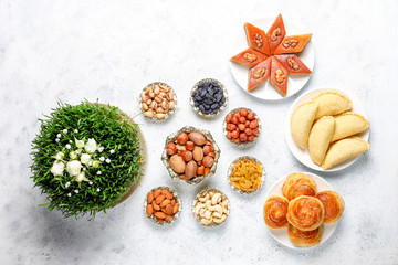 Novruz Azerbaijan traditional table setting, delicious sweet pastry on light background with green wheat grass semeni. Golden plate of pakhlava and shekerbura and gogal, copy space