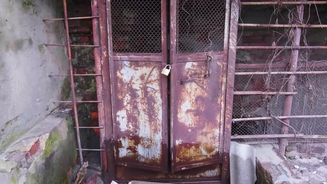 Entrance to an old abandoned ruined building, iron old rusty doors closed with a padlock