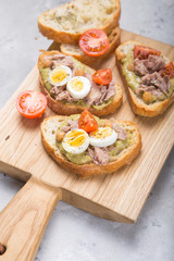 Bruschetta with tuna, tomato, egg, and avocado spread.