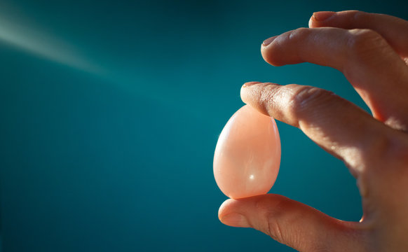 woman holding a pink quartz yoni egg