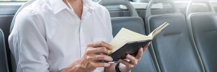 Concept of commute, public transportation, mobility. handsome young businessman sitting and reading book on bus public transport.