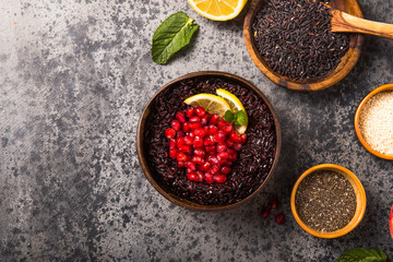 Cooked Thai black jasmine rice with chia seeds,pomegranate,  lemon, sesame on concrete grey  background. Top view copy sapce
