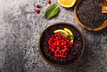 Cooked Thai black jasmine rice with chia seeds,pomegranate,  lemon, sesame on concrete grey  background. Top view copy sapce