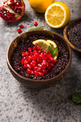 Cooked Thai black jasmine rice with chia seeds,pomegranate,  lemon, sesame on concrete grey  background. Top view