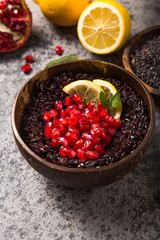 Cooked Thai black jasmine rice with chia seeds,pomegranate,  lemon, sesame on concrete grey  background. Top view