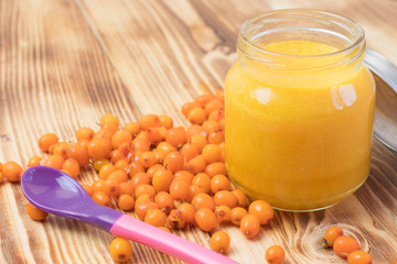 baby sea buckthorn puree in a jar on a wooden table. baby food.