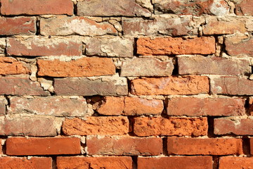 Background texture of old dilapidated red brick wall with cracked concrete patches on front wall of suburban family house without facade wallpaper