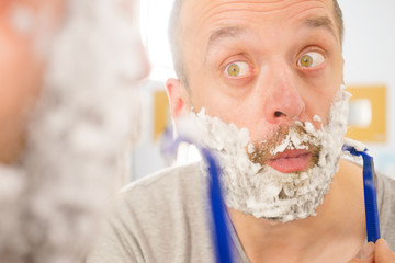 Guy shaving his beard in bathroom