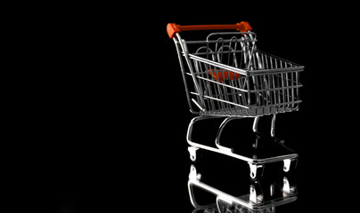 Empty metal supermarket trolley or shopping cart isolated on black background with copy space. Concept of sales ,  discounts , shopping, e-shopping, business and ecology