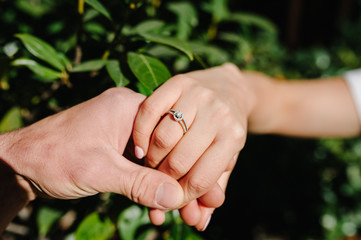 Man holding his girlfriend's hand. Man making a marriage proposal to his girlfriend - Happy engaged couple holding hands. Love, family, anniversary concept.