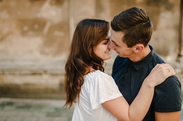 Fototapeta premium Loving young couple kissing and hugging in st valentine's day at the city. Love and tenderness, dating, romance, family, anniversary concept.