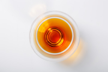 A glass of whiskey stands on a white background. The view from the top