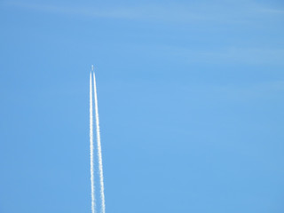 Airplane flying in the clear blue sky and contrail against, Engine exhaust contrails forming behind,  Jet contrails or trails over blue sky and clouds.