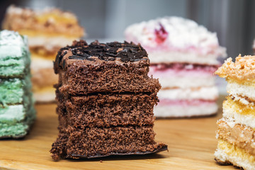 assorted sponge cakes with different fillings on the window of the pastry shop. Focus on chocolate with nuts cake