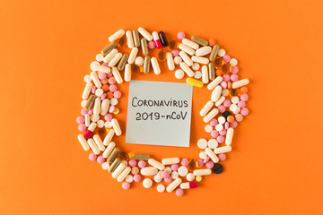 CORONAVIRUS. 2019-nCoV.  A bunch of pills and the inscription CORONAVIRUS 2019-nCoV on a protective medical mask on an orange background. The concept of virus protection.