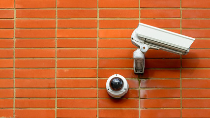 Two Different CCTV Cameras on a Red Brick Wall