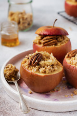 Baked Apples Stuffed with pecans, cinnamon, streyzel and honey on old concrete light background. Rustic stale.