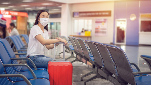Asian tourist with luggage ,wearing hygienic mask to prevent during travel time at the airport terminal for protect from the Coronavirus 2019 (COVID-19) infection outbreak situation