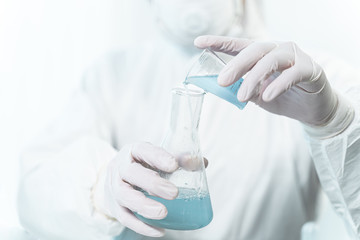 Professional researcher adding blue liquid into bottle