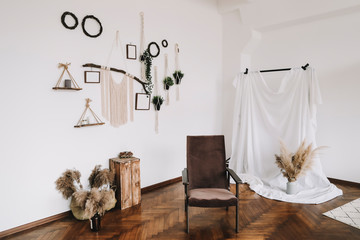 Home interior design with mock up posters on the wall, handmade macrame, brown comfortable chair.  scandi-boho style. 