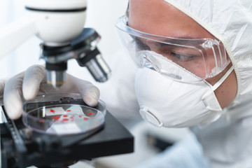 Concentrated Asian scientist staring at blood drops