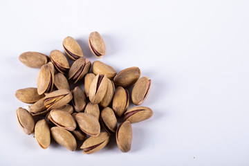 Pistachios on the left side of a white background