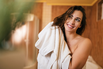 Young beautiful woman using towel and drying her hair in the bathroom.