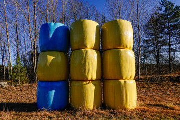 Obraz premium Norrtalje, Sweden Hay bales in a field covered in breathable plastic colored in yellow and blue, the colors of the Swedish fla.